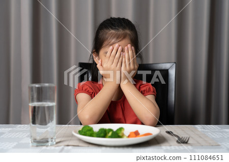 Little cute kid girl refusing to eat healthy vegetables. Children do not like to eat vegetables. Little cute kid girl refusing to eat healthy vegetables. Children do not like to eat vegetables. 111084651
