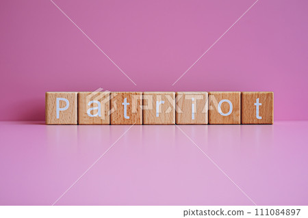 Wooden blocks form the text "Patriot" against a pink background. Wooden blocks form the text "Patriot" against a pink background. 111084897