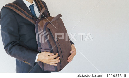 Businessman holding a backpack in front of him Businessman holding a backpack in front of him 111085846