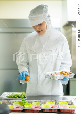 A young woman in a clean suit packs side dishes A young woman in a clean suit packs side dishes 111088522
