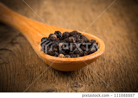 black pepper on wooden spoon 111088887