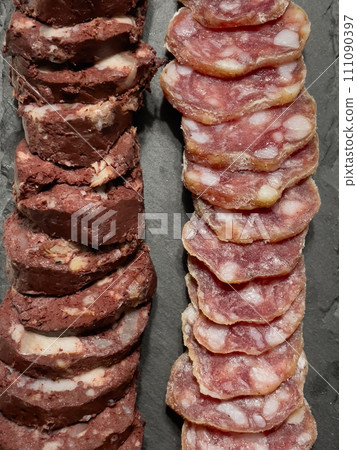 Slices of sausage and meat pudding on a plate, top view 111090397