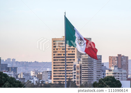 Mexico City, Mexico. Jan 11, 2024. On a winter afternoon in downtown Mexico City, a large Mexican flag gracefully flutters in the breeze. Mexico City, Mexico. Jan 11, 2024. On a winter afternoon in downtown Mexico City, a large Mexican flag gracefully flutters in the breeze. 111090614