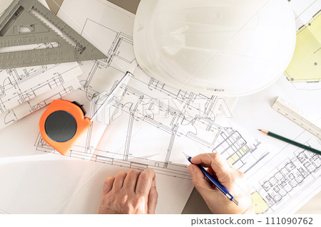 Top view of a contractor hands with pencil working on Architecture plans on desk Top view of a contractor hands with pencil working on Architecture plans on desk 111090762