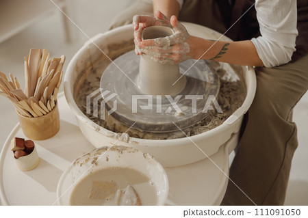 Close up of artisan's hands shaping clay bowl in pottery studio. Pottery art and creativity Close up of artisan's hands shaping clay bowl in pottery studio. Pottery art and creativity 111091050