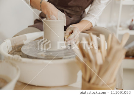 Close up of hands of professional potter molding pot shape on pottery wheel. Ceramics art concept Close up of hands of professional potter molding pot shape on pottery wheel. Ceramics art concept 111091093