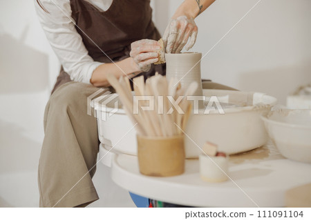 Close up of hands of professional potter molding pot shape on pottery wheel. Ceramics art concept Close up of hands of professional potter molding pot shape on pottery wheel. Ceramics art concept 111091104