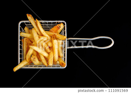 An aerial perspective of a modest basket containing French fries, set against a dark backdrop. An aerial perspective of a modest basket containing French fries, set against a dark backdrop. 111091569