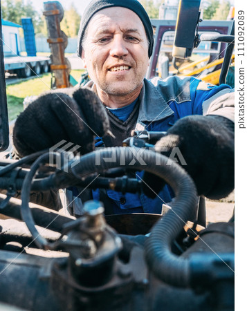 Mechanic repairs engine of tractor or heavy equipment. Farmer inspects and diagnoses agricultural Mechanic repairs engine of tractor or heavy equipment. Farmer inspects and diagnoses agricultural 111092089