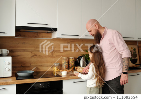 Girl helping father prepare breakfast Girl helping father prepare breakfast 111092554