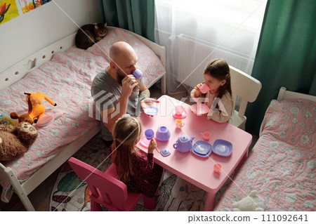 Man and little girls having tea together 111092641