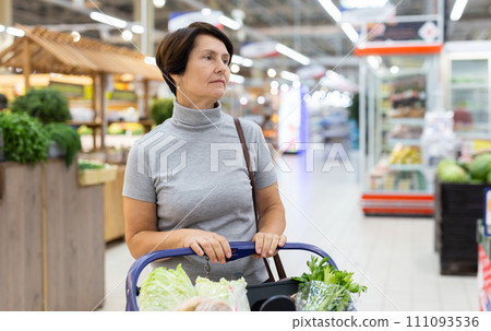 Elderly woman with shopping cart shopping in supermarket Elderly woman with shopping cart shopping in supermarket 111093536