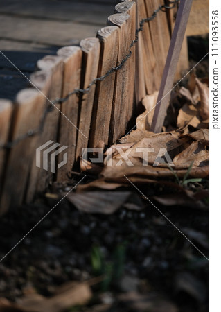 Wooden fence and fallen leaves Wooden fence and fallen leaves 111093558