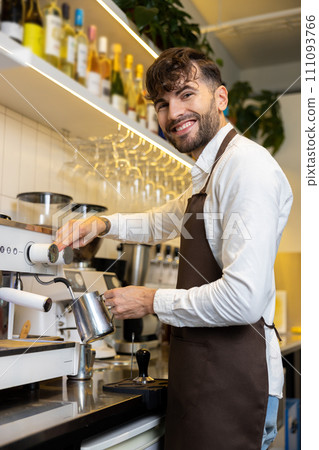 Smiling barista standing near coffee machine and looking contented Smiling barista standing near coffee machine and looking contented 111093766