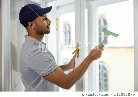 Man washing window doing household chores at home. 111093879