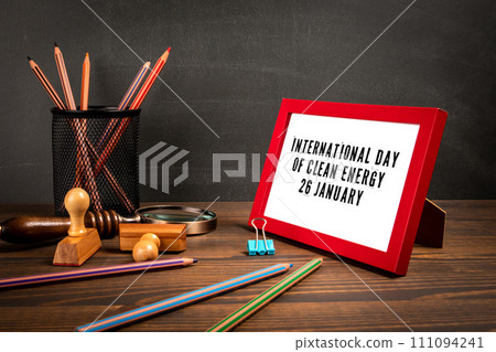 International Day of Clean Energy 26 January. Red picture frame with text on wooden table 111094241