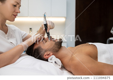 Beautician working with a customer and using current therapy 111094875
