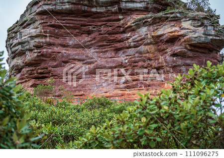 Majestic Red Sandstone Cliff Surrounded by Lush Greenery 111096275