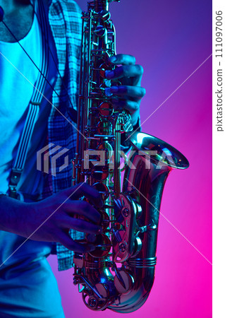 Close up photo of musician's hands playing jazz chord against pink-blue background in mixed neon light. Improvisation. Close up photo of musician's hands playing jazz chord against pink-blue background in mixed neon light. Improvisation. 111097006