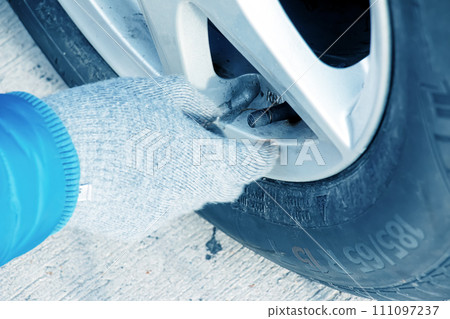 Hand holds the pressure gauge and fills the car tires with air. Car maintenance. 111097237