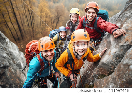 Group of teen friends climbing on a rock in the autumn forest. Looking at camera. Climbing equipment. 111097636