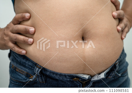 Overweight Asian woman show and use hand to squeeze fat belly. 111098581