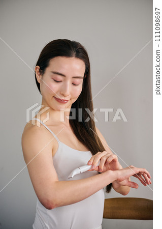 A woman in her 30s shaving her arm hair with an electric shaver A woman in her 30s shaving her arm hair with an electric shaver 111098697