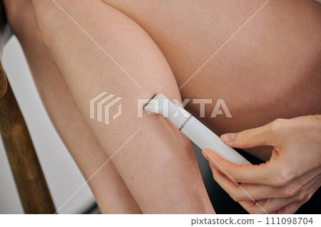 一名30多歲的女士用電動刮鬍刀剃頭髮 一名30多歲的女士用電動刮鬍刀剃頭髮 111098704