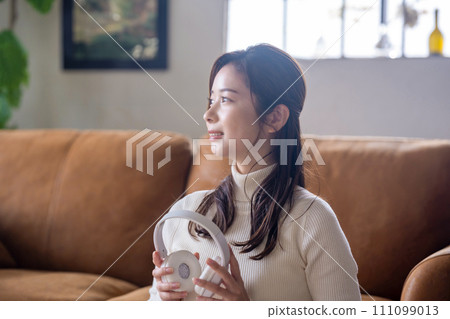 A woman listening to music with headphones 111099013