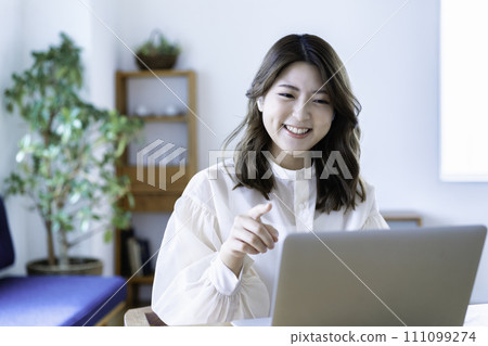 Young woman having an online meeting in the living room Young woman having an online meeting in the living room 111099274