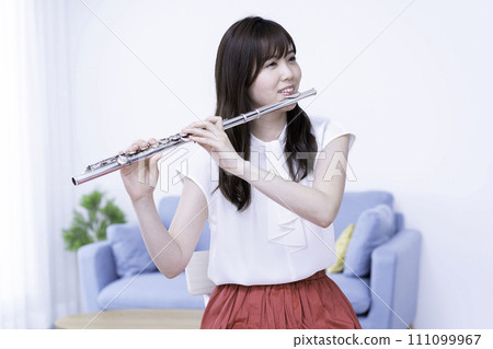 Woman playing the flute in the living room 111099967