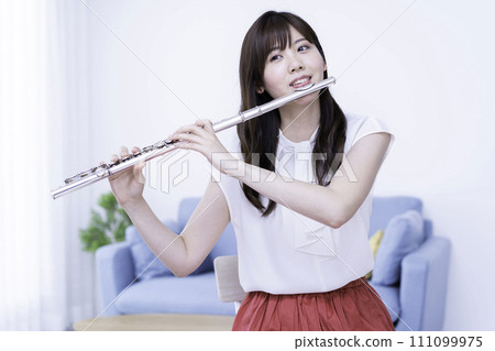 Woman playing the flute in the living room 111099975