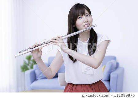 Woman playing the flute in the living room 111099976