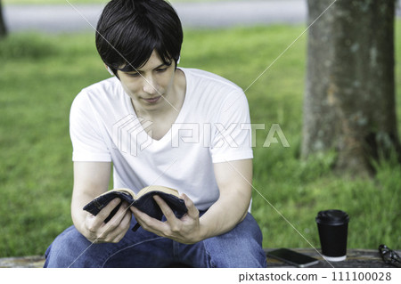 一個外國男人在清新的綠色公園裡邊聽音樂邊讀書 一個外國男人在清新的綠色公園裡邊聽音樂邊讀書 111100028