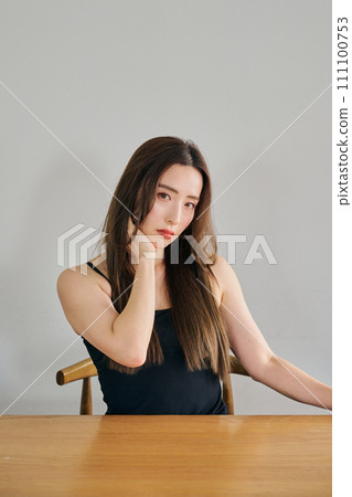 A woman in her 30s with long hair wearing a black camisole A woman in her 30s with long hair wearing a black camisole 111100753
