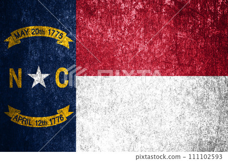 Close-up of the grunge North Carolina state flag. Dirty North Carolina state flag on a metal surface. 111102593