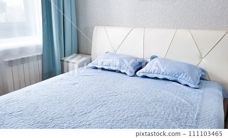 modern bedroom interior with a modern upholstered headboard, a white bed with a cozy blanket 111103465