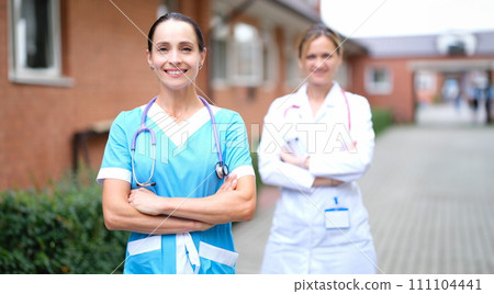 Female doctors in uniforms standing near clinic Female doctors in uniforms standing near clinic 111104441