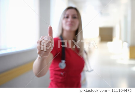 Woman doctor in red uniform showing thumb up closeup Woman doctor in red uniform showing thumb up closeup 111104475