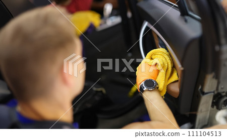 Male cleaner wiping dust in interior of car with microfiber cloth closeup 111104513