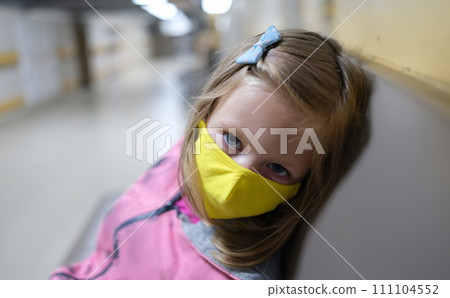 Little girl in yellow protective medical mask sitting in hospital corridor Little girl in yellow protective medical mask sitting in hospital corridor 111104552