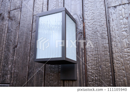 Modern external lamp on burned wood wall Modern external lamp on burned wood wall 111105940