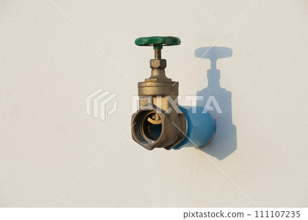 Water shut off valve installed on white wall with shadow. 111107235