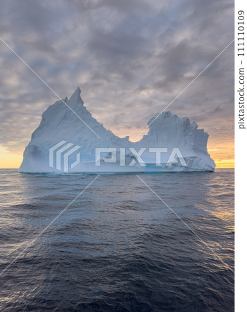 A huge high breakaway glacier drifts in the southern ocean off the coast of Antarctica at sunset, the Antarctic Peninsula, the Southern Arctic Circle, azure water, cloudy weather A huge high breakaway glacier drifts in the southern ocean off the coast of Antarctica at sunset, the Antarctic Peninsula, the Southern Arctic Circle, azure water, cloudy weather 111110109