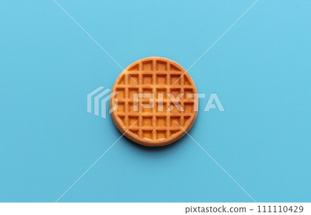 Round waffle directly above view, isolated on a blue background Round waffle directly above view, isolated on a blue background 111110429
