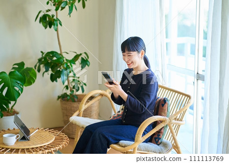 Young woman operating a smartphone in the room 111113769