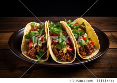 Juicy beef tacos topped with veggies side by side on the black plate on wooden table 111113835