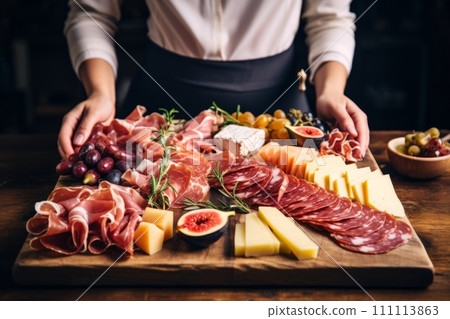 Womans hands holding wine and charcuterie board on black background. Italian antipasti or Spanish tapas 111113863