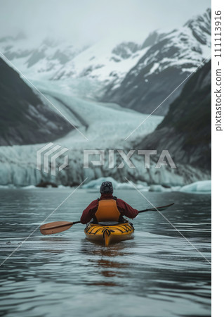 A man paddling in a kayak through the glacial lake with glacier in background 111113916