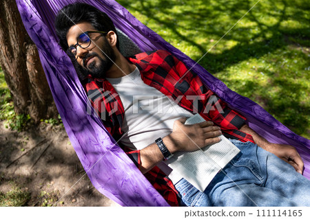 Brunette young man sleeping in hammock in the park 111114165